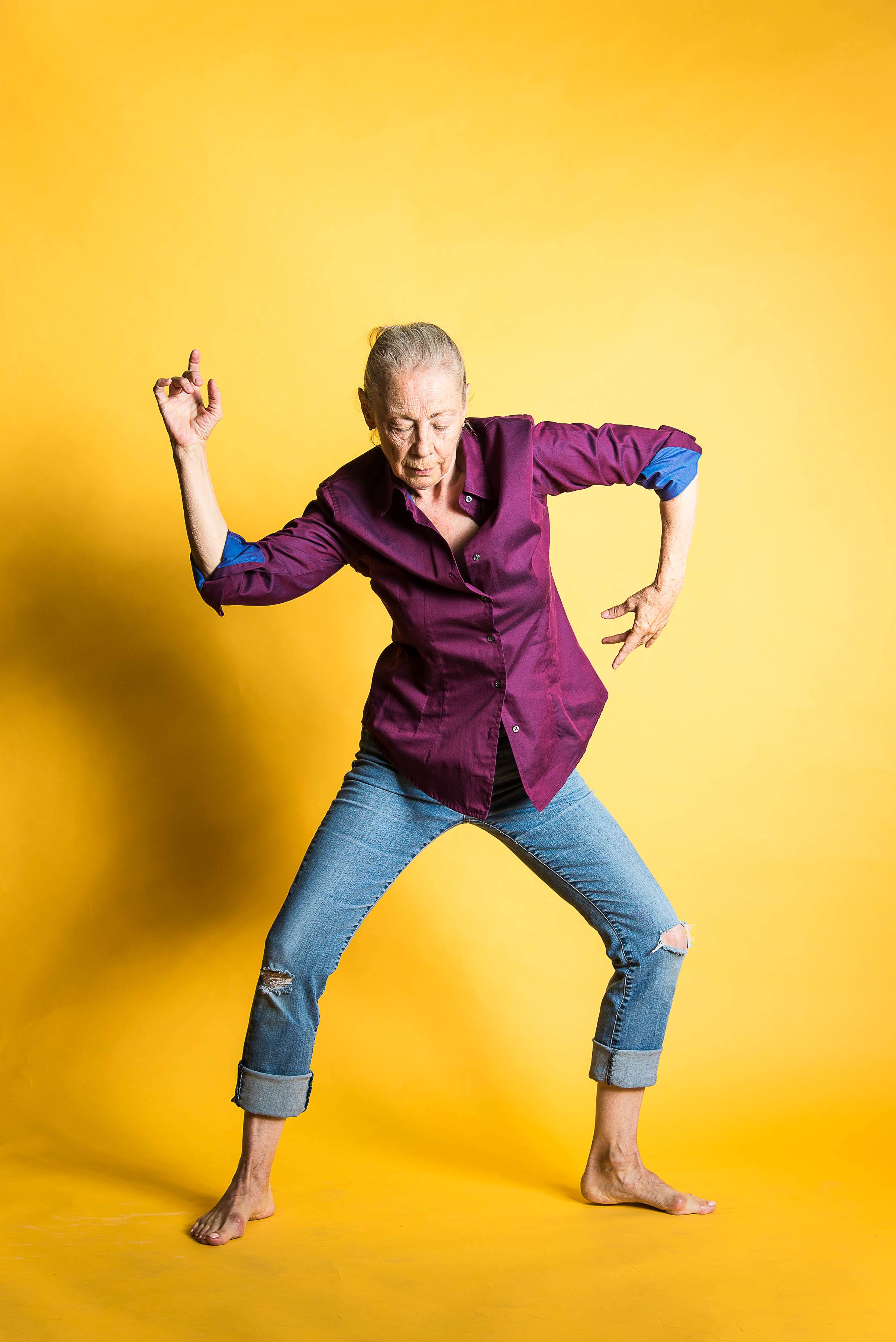 Debbie Wilson in a freestyle dance pose against a yellow backdrop.